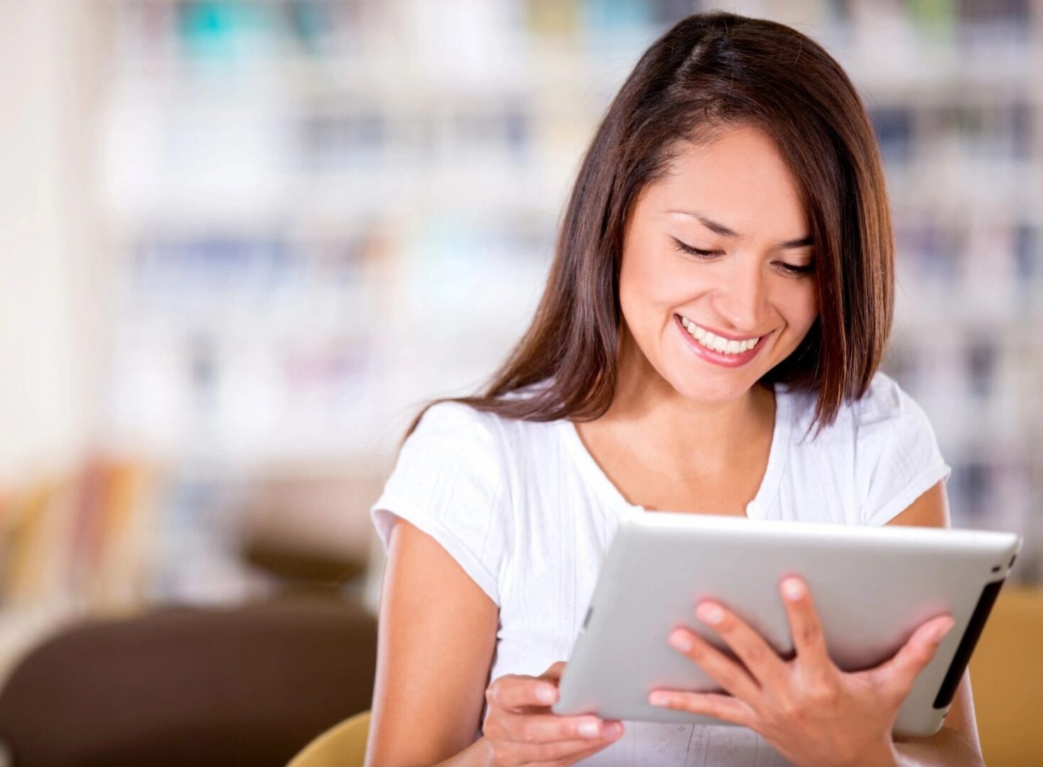 A woman is smiling while using her tablet.